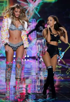 Modelul Candice Swanepoel (stînga, evident), pe scenă alături de cîntăreața Ariana Grande